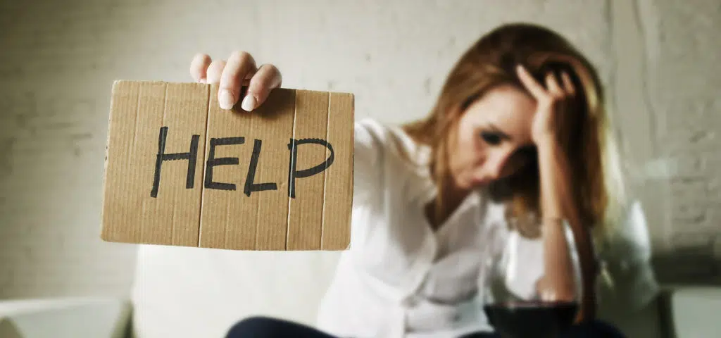 woman drinking wine holding a sign up for help