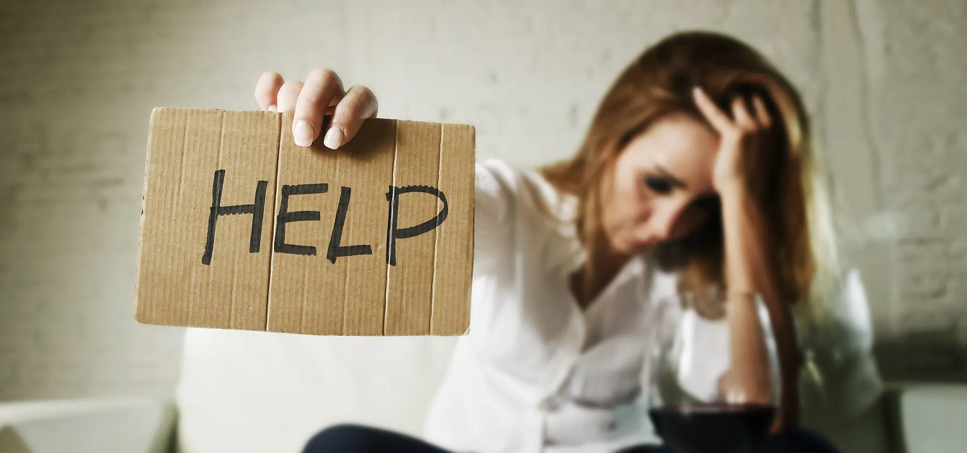 woman drinking wine holding a sign up for help