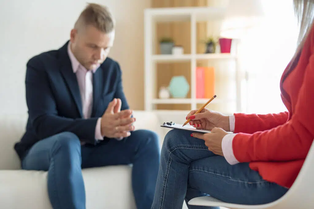 man with signs of addiction meeting with therapist