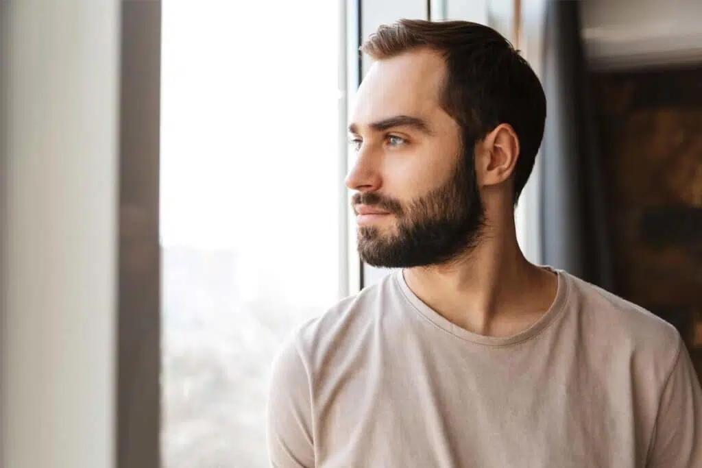 man looking out window hopefully for Overcoming Codependency