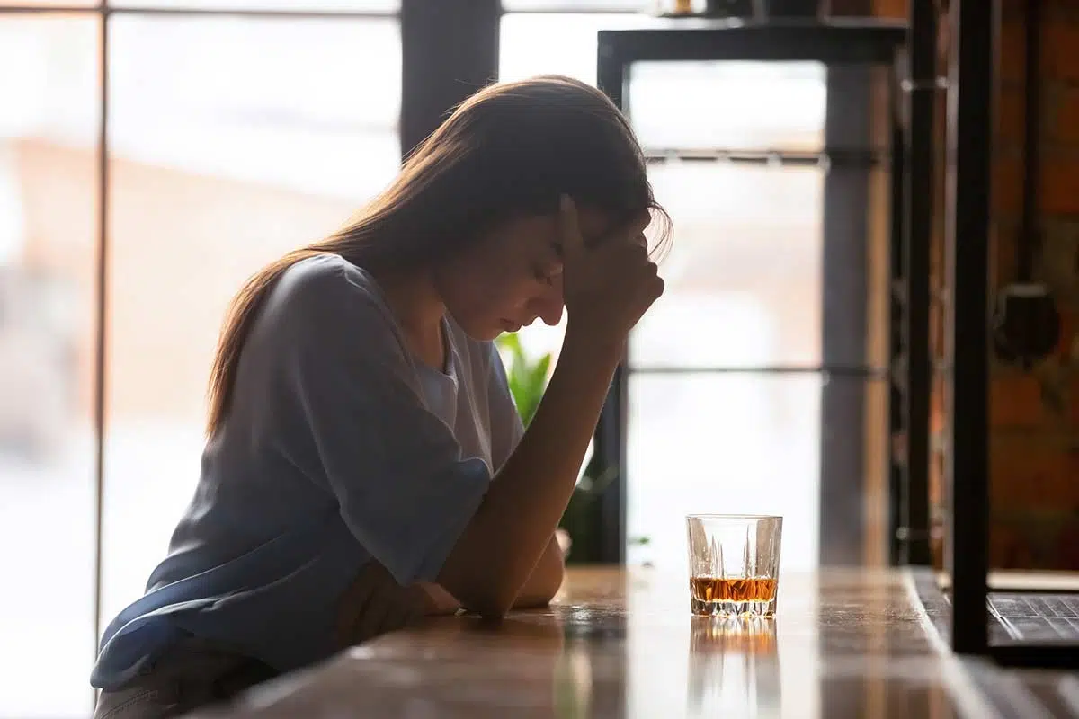 woman at bar over a drink dealing with alcohol abuse