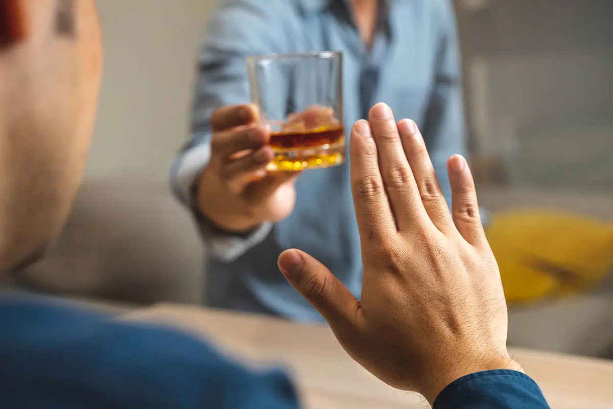 person waving off a drink for the benefits of not drinking alcohol